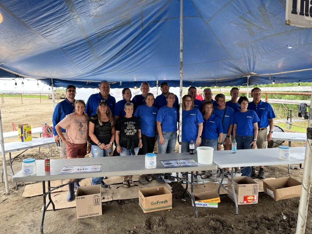 Centennial Homes team in blue shirts volunteering under a tent at an outdoor community event