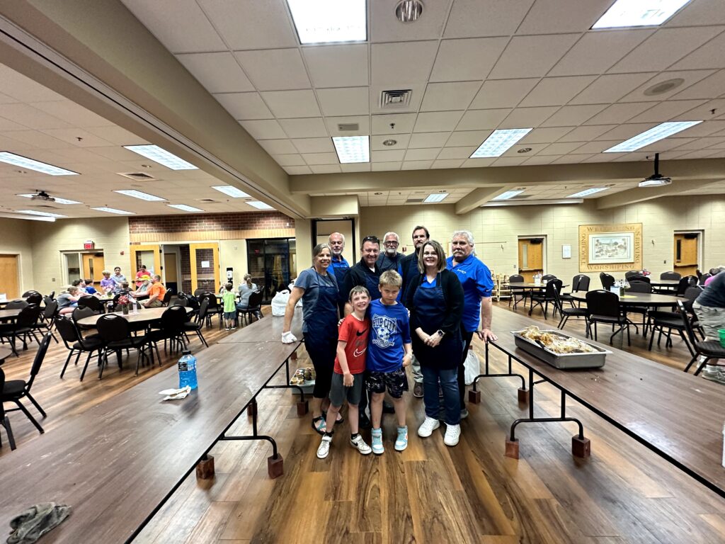 Centennial Homes volunteers with families in a dining hall at a community meal