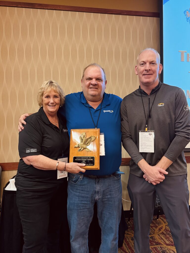 Three people holding an award plaque for Number 1 in homes sold for 2024