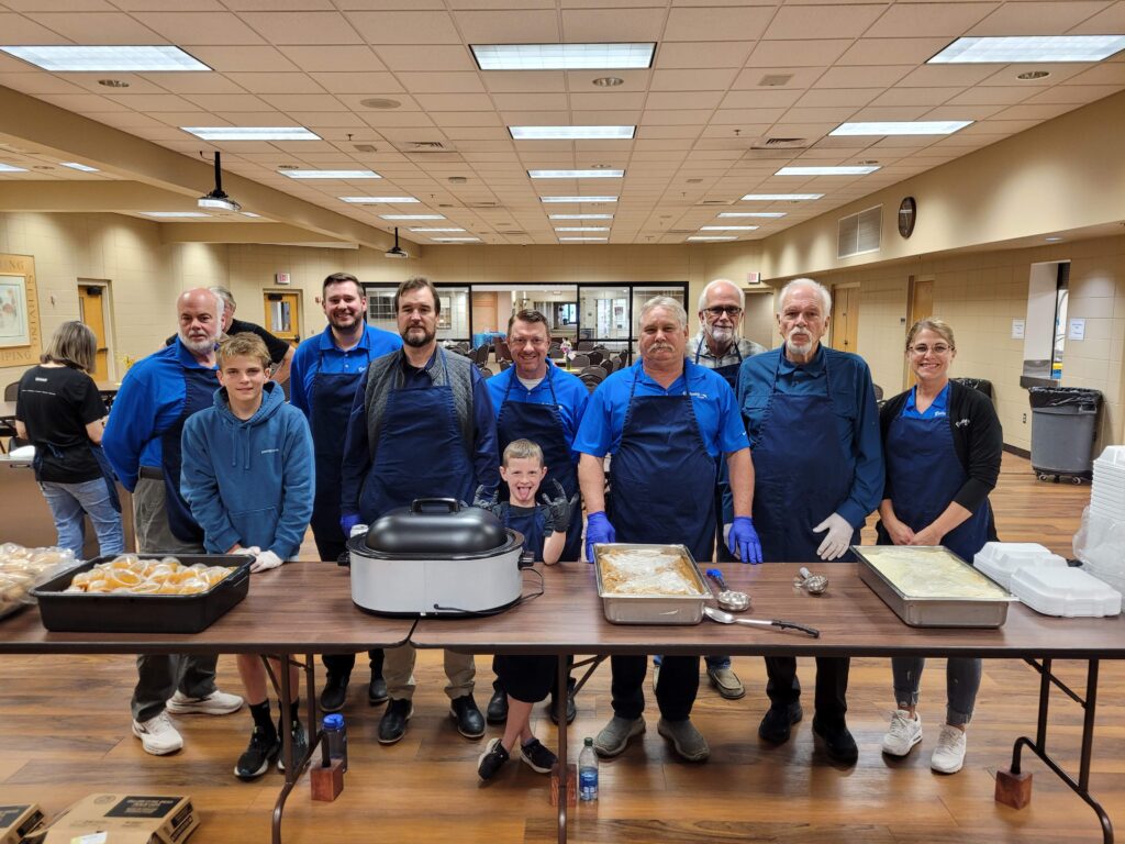 Centennial Homes volunteers in aprons serving a community meal